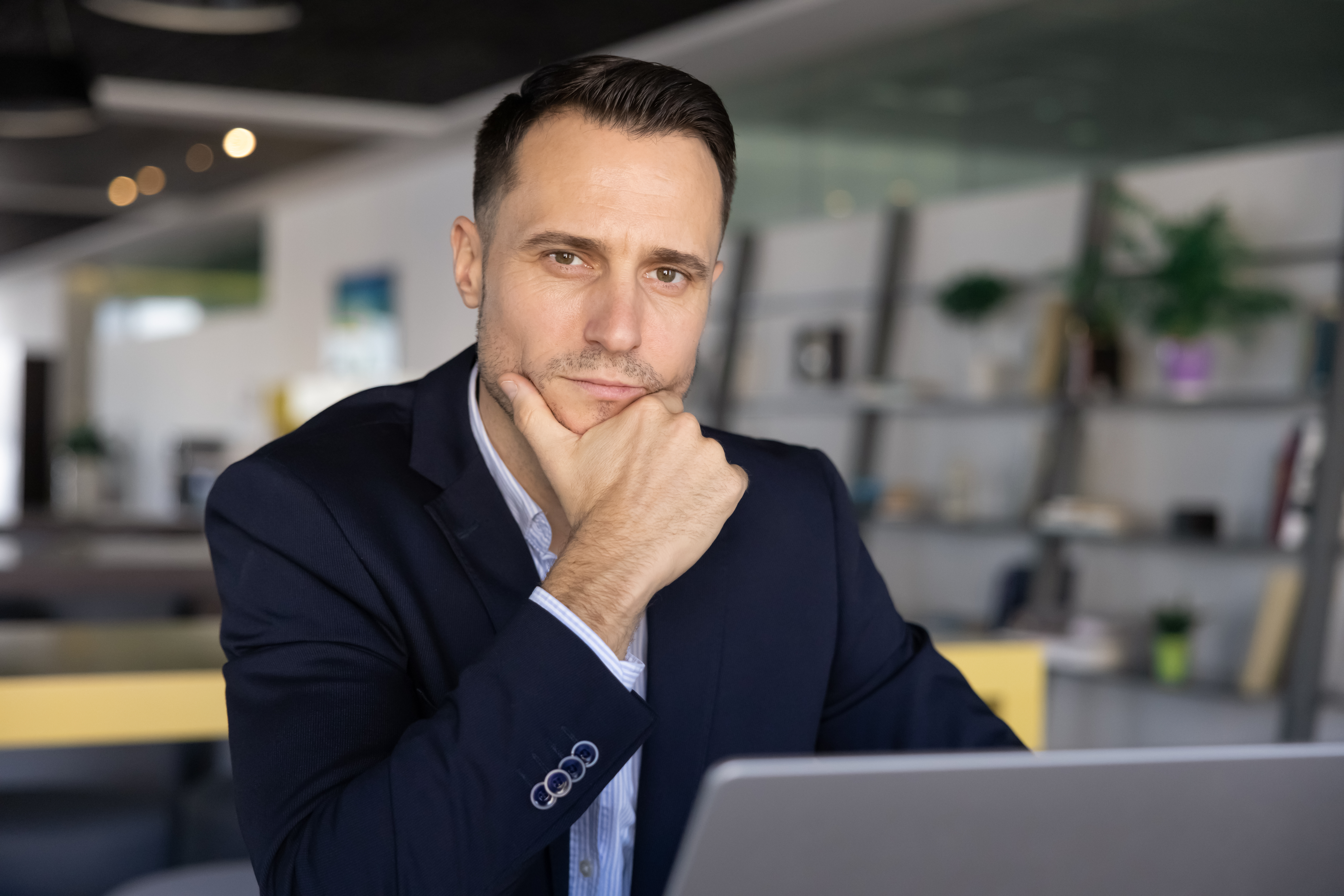 Serious confident young Latin business man posing at workplace