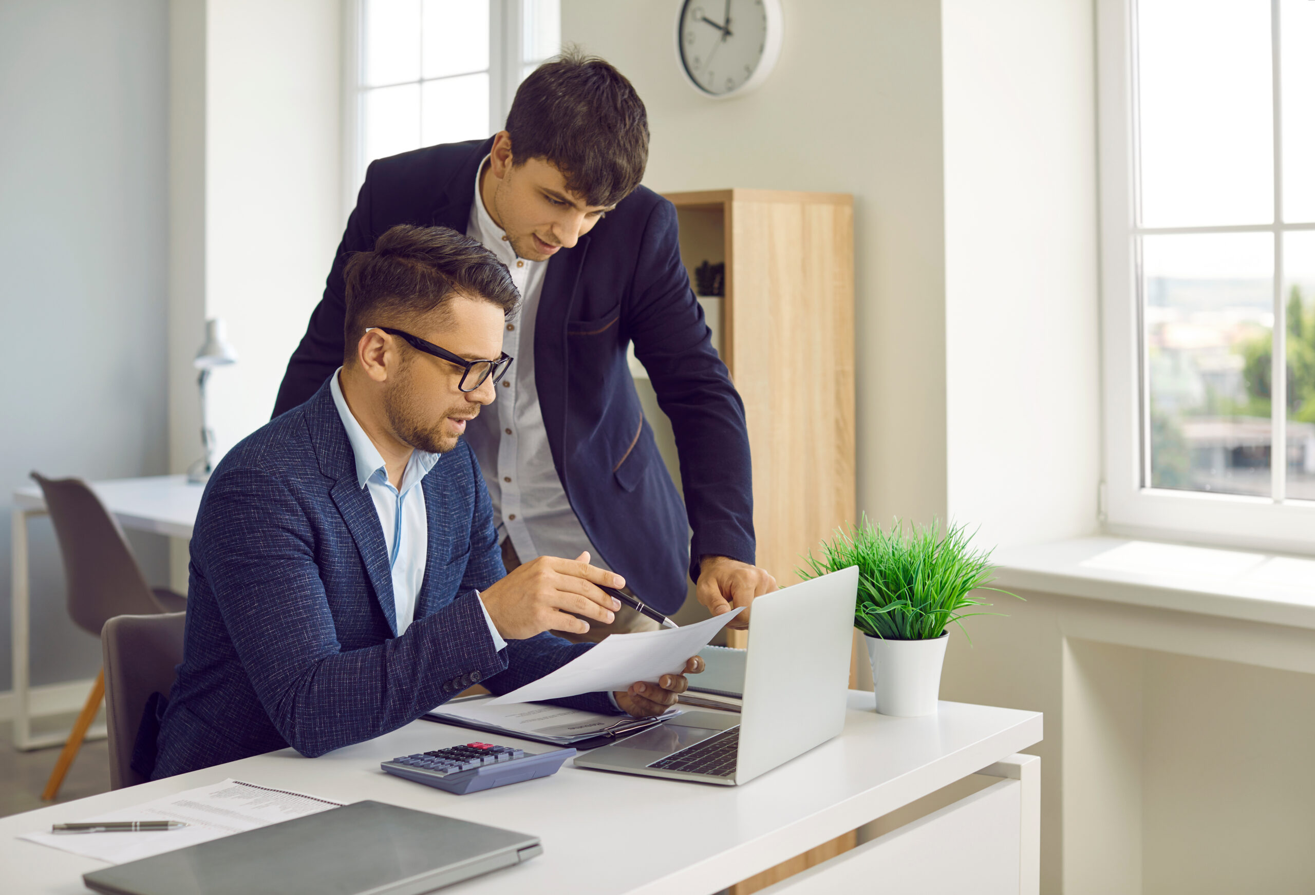 Male financial director giving directions to his assistant while working on financial report.